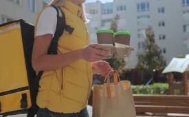 woman_food_courier_in_uniform_carrying_food_in_paper_bag_and_takeaway