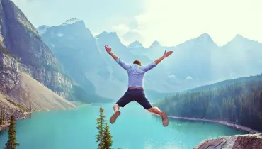 man-mountains-background-jump-arms-spread-out-personality-traits-all-successful-people-share