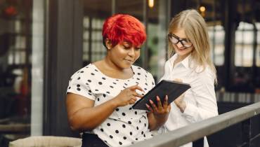 two-female-entrepreneurs-experience-tablet-smiling-colleagues