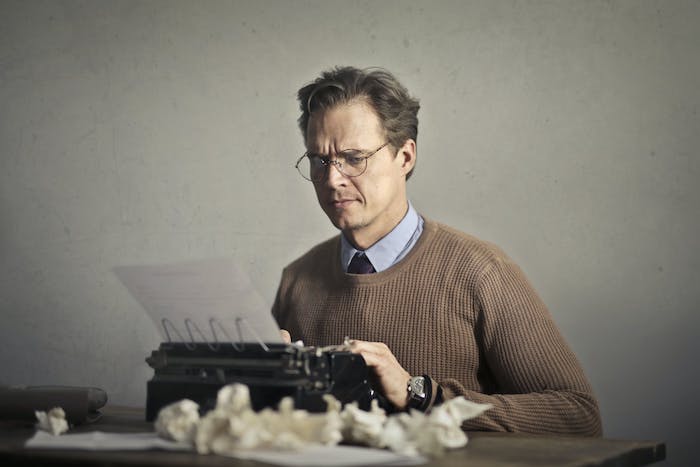 male_writer_working_on_typewriter_at_home.jpeg
