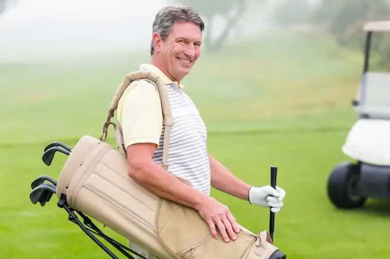 Happy golfer with golf buggy behind