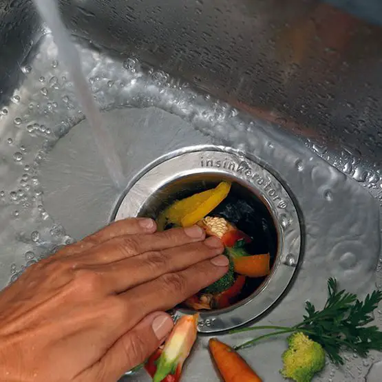 Person Flushing Kitchen Food Waste Into Garbage Disposal Unit