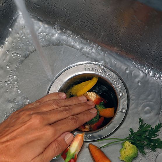 Person Flushing Kitchen Food Waste Into Garbage Disposal Unit