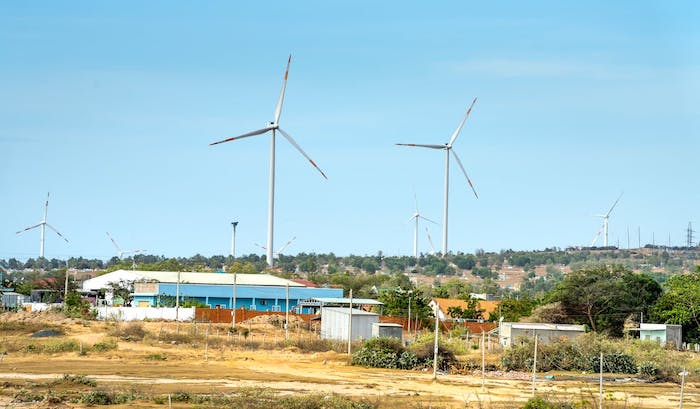 Windmills against trees and buildings in countryside
