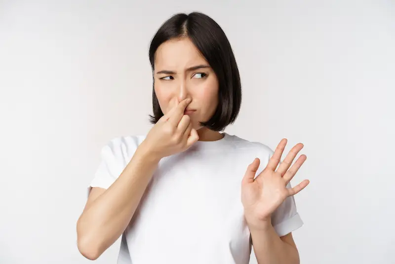 asian-girl-looks-disgusted-bad-smell-shut-nose-standing-against-white-background