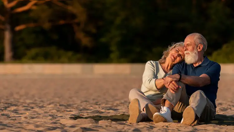 full-shot-senior-couple-sitting-sand-love
