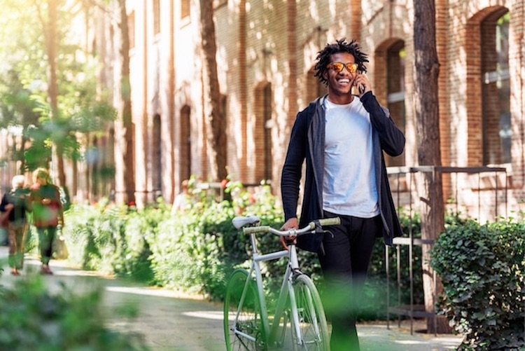 Man using mobile phone walking with bicycle in the street