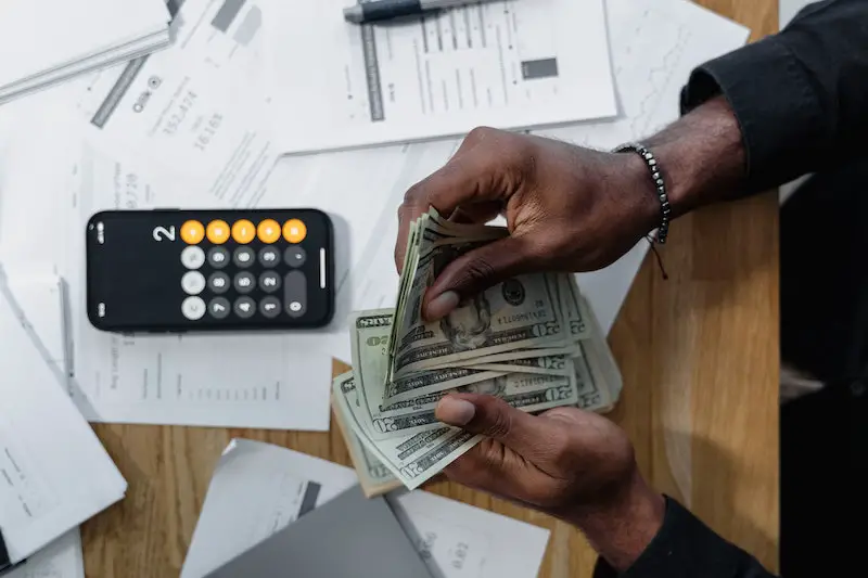 man-hand-counting-dollar-bills-calculator-payrol-documents