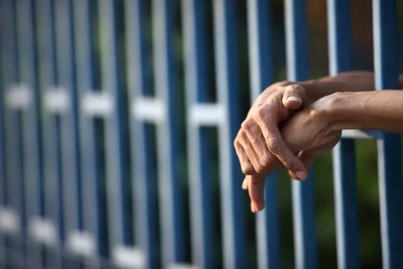 mans-hands-incarceration-prison-cell