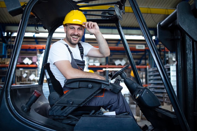 Smiling professional forklift driver factory warehouse.