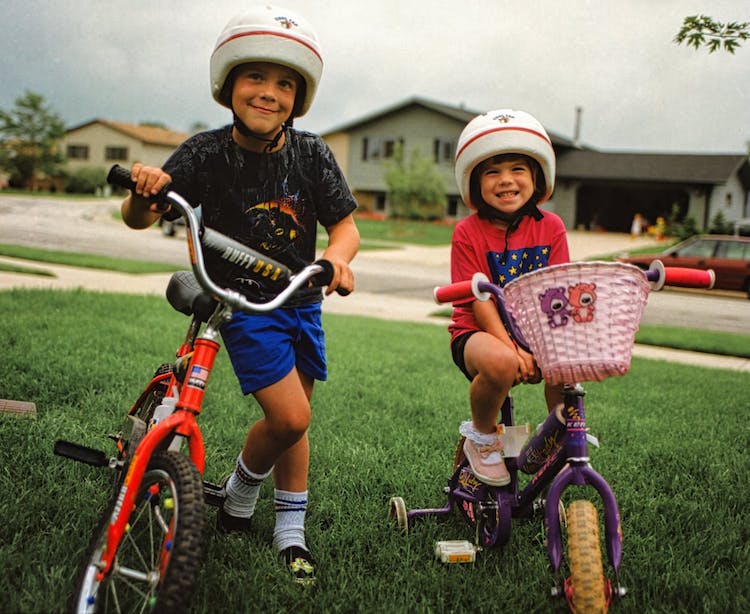 kids-boy-girl-happy-riding-bicycles-outside-green-grass.