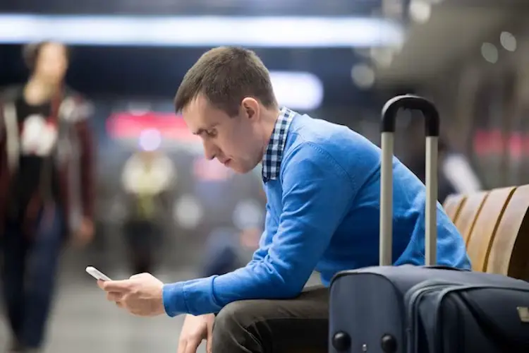 Young man traveler waiting airport browsing smartphone