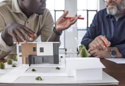 Two Men Property Models on Table Commercial vs. Residential Investment