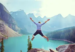 man-mountains-background-jump-arms-spread-out-personality-traits-all-successful-people-share