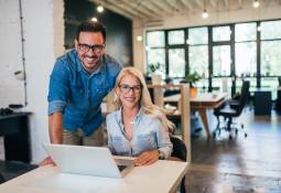 two-small-business-owners-male-female-using-laptop-smiling