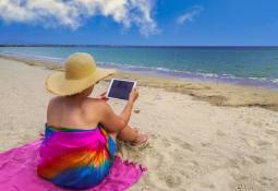 woman-holidaymaker-using-tablet-on-the-beach