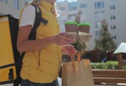 woman_food_courier_in_uniform_carrying_food_in_paper_bag_and_takeaway