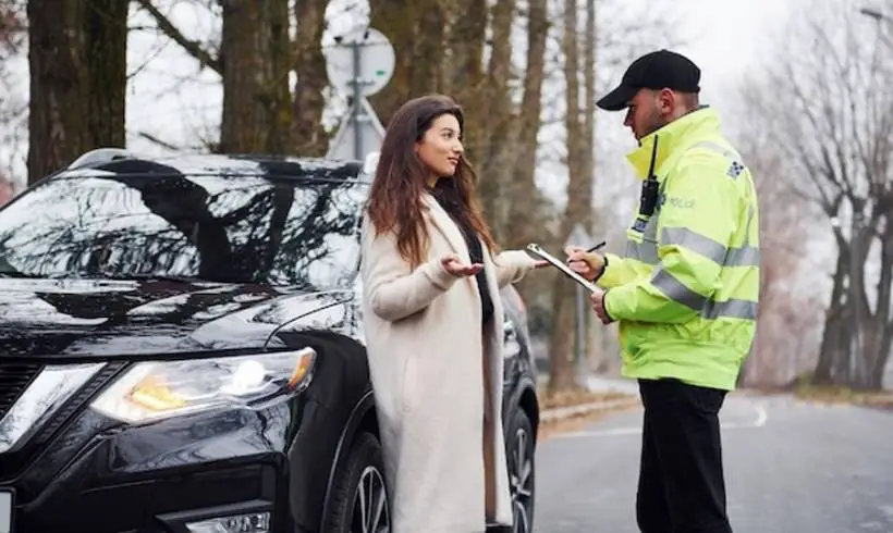 Male police officer in green uniform talking with female car owner