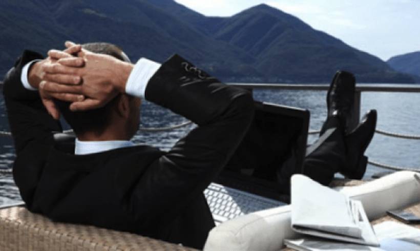 man-suit-relaxing-feet up-ship-deck-laptop-on-deck 