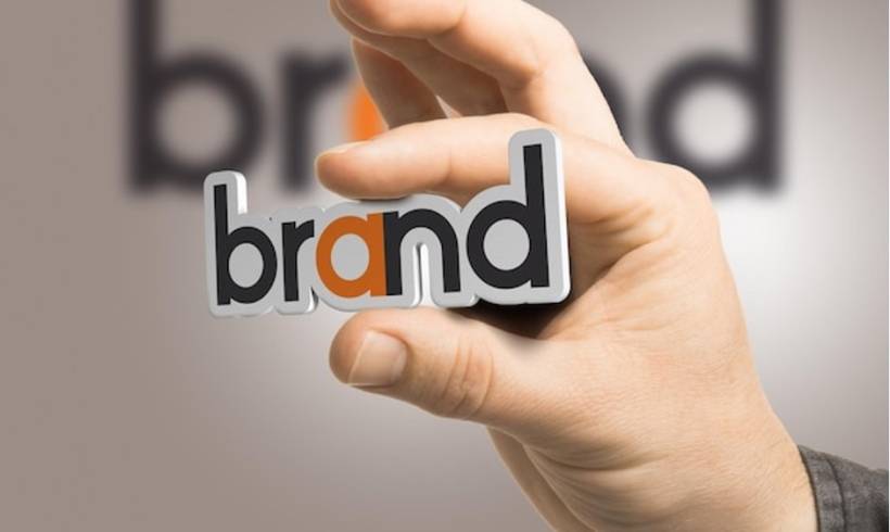 One hand holding the word brand over a beige background