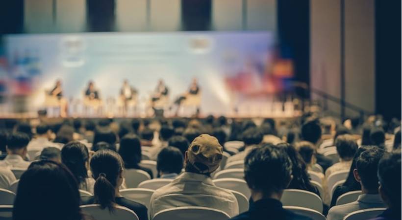 Rear view of audience listening speakers on the stage at a business event conference.j