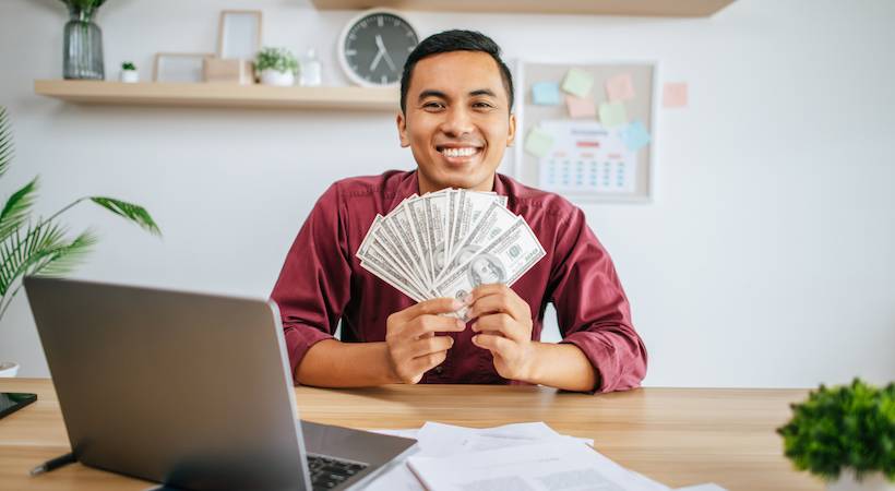 man-working-office-holding-money-with-laptop-documents-desk-startup-funds