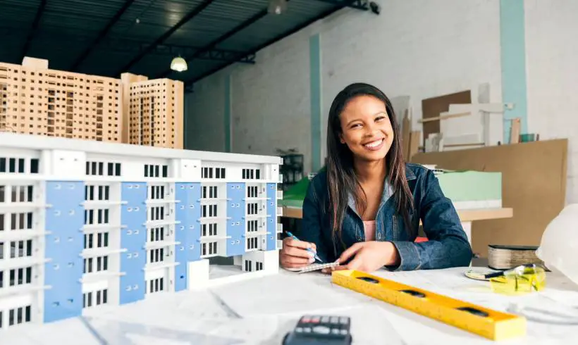 Smiling Businesswoman model of building Image for How to Start a Real Estate Business with No Money Out of Your Pocket