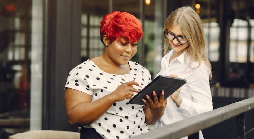 two-female-entrepreneurs-experience-tablet-smiling-colleagues