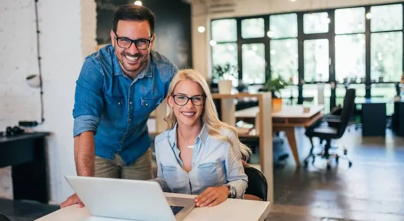 two-small-business-owners-male-female-using-laptop-smiling