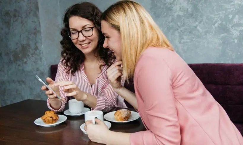 two-women-checking-smartphone-social-media-marketing-happy