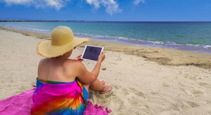 woman-holidaymaker-using-tablet-on-the-beach