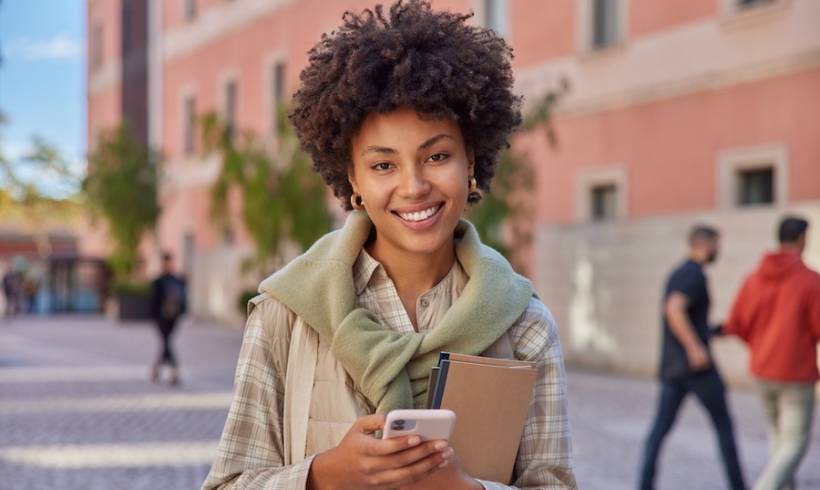 young-woman-student-holds-smartphone-outside-school-money-saving-app