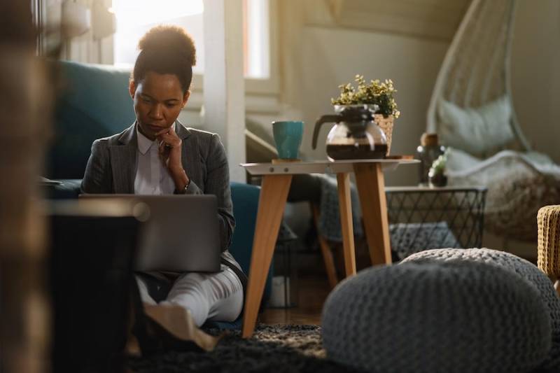 businesswoman working on a computer while siting on the floor at home office side hustle