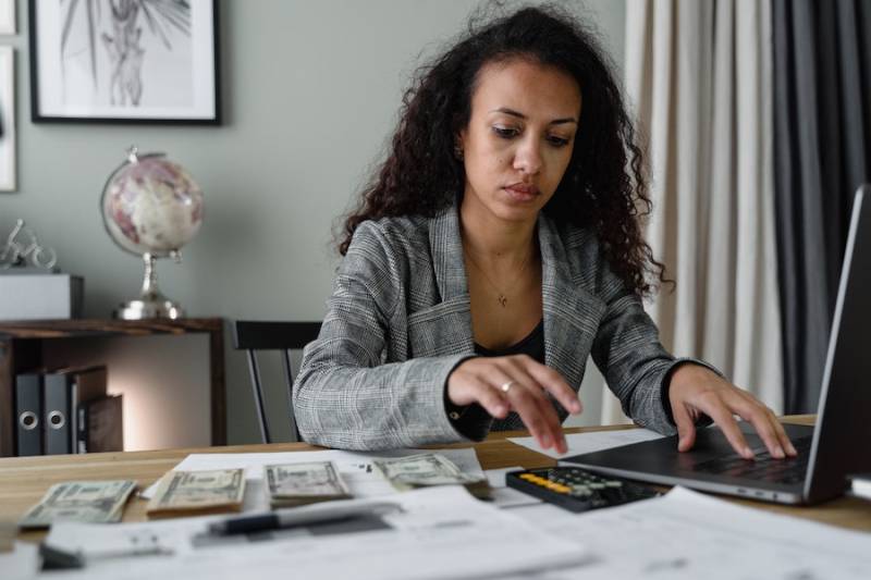 businesswoman_money_on_table_using_laptop_payroll_software