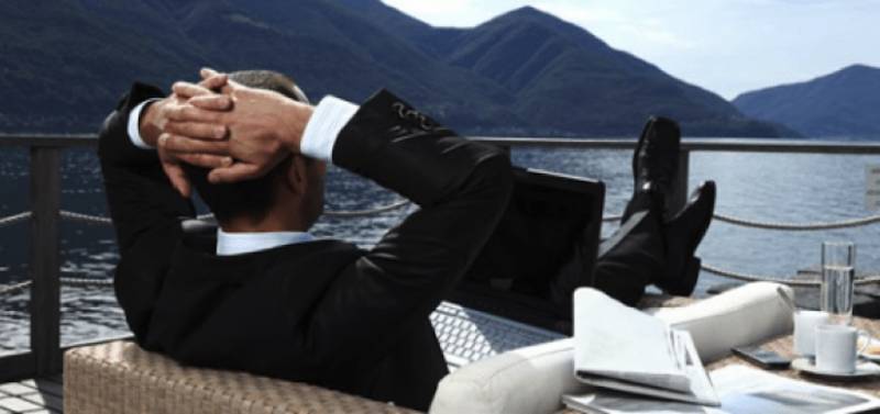 man-suit-relaxing-feet up-ship-deck-laptop-on-deck 