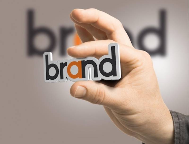One hand holding the word brand over a beige background