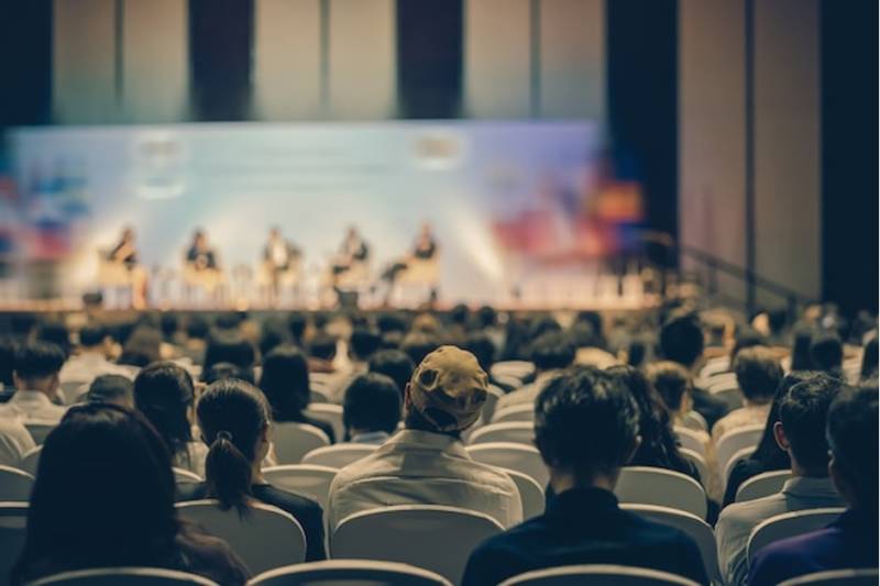 Rear view of audience listening speakers on the stage at a business event conference.j