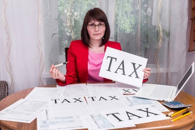 Woman_showing_word_tax_on_sheet_of_paper