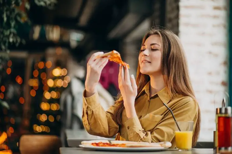 young_woman_eating_pizza_place