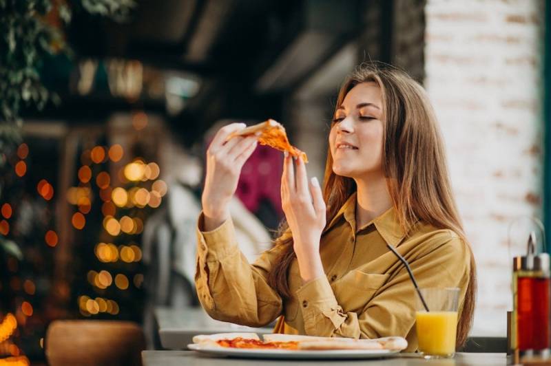 young_woman_eating_pizza_place