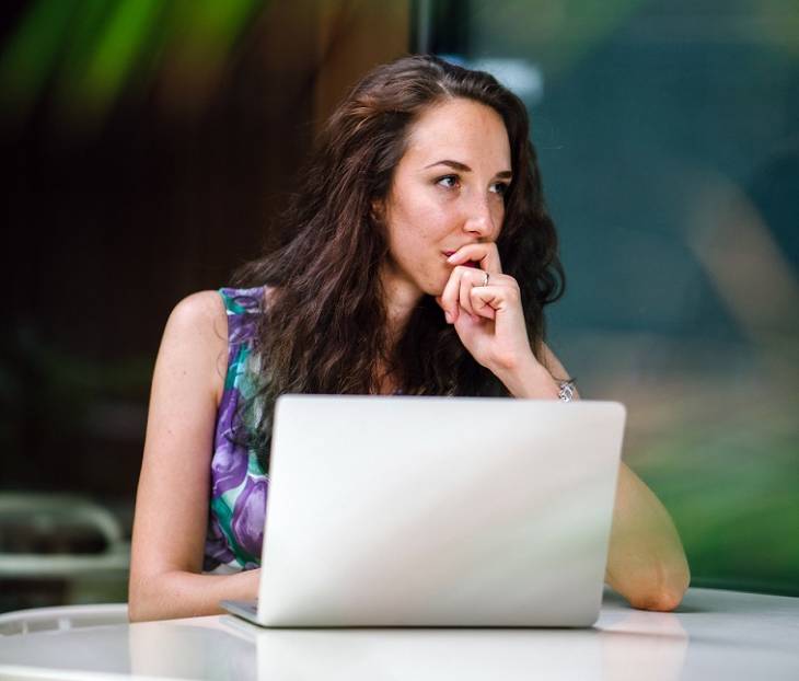 female-sitted-laptop-on-table-contemplationg-setting-goals