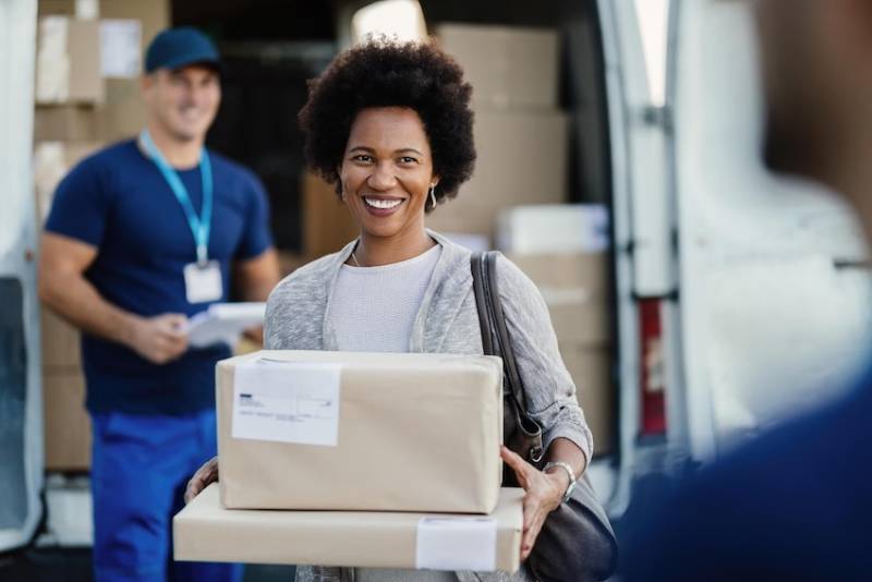 happy-african-american-woman-holding-delivered-packages-couriers-is-standing-background