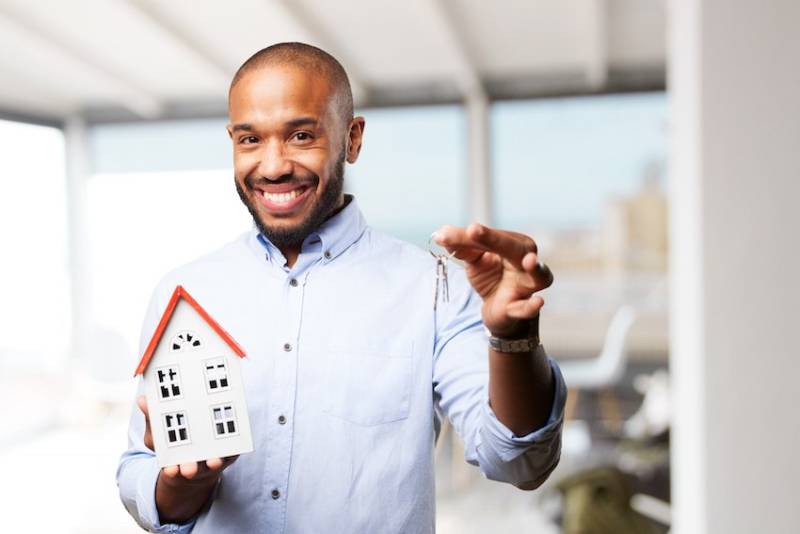 Man Happy Holding House Model and Keys to Property Image for Key Factors to Consider When Buying a Real Estate Property