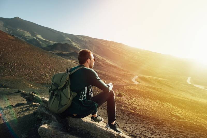 man-with-rucksack-sitting-rock-sunset-mountain-nature-for-creative-inspiration-inner-healing 