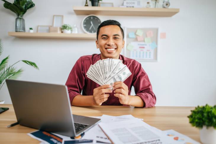 man-working-office-holding-money-with-laptop-documents-desk-startup-funds