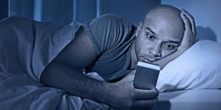 man-reading-on-smartphone-in-bed-mass_text_messaging