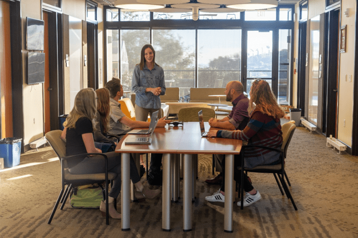 female-coach-speaking-with-team-members-office