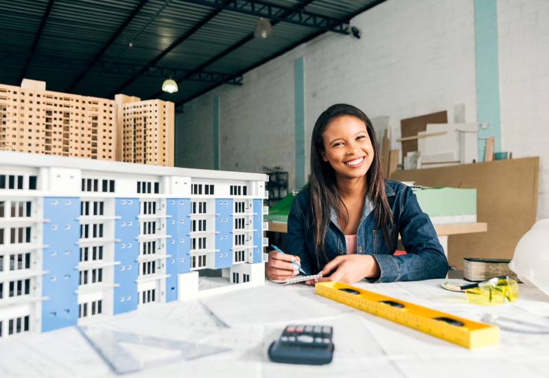 Smiling Businesswoman model of building Image for How to Start a Real Estate Business with No Money Out of Your Pocket