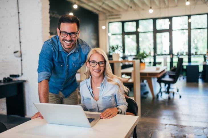 two-small-business-owners-male-female-using-laptop-smiling