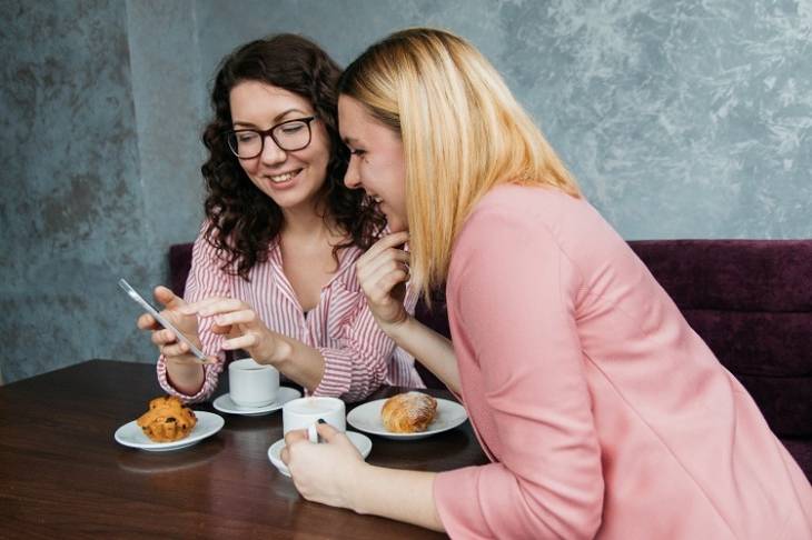 two-women-checking-smartphone-social-media-marketing-happy